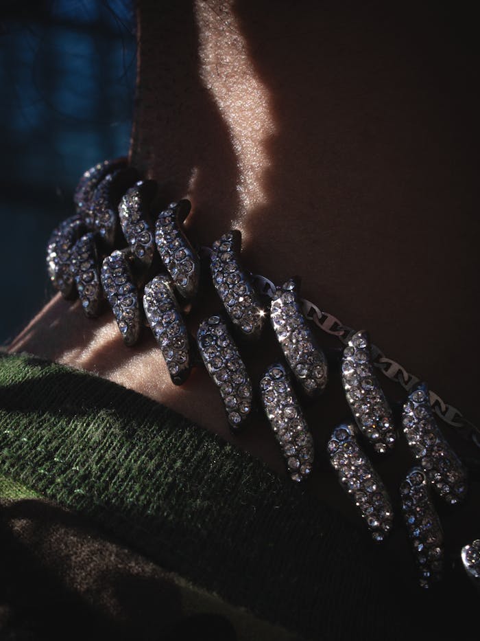 Intricate diamond chain necklace captured in a dramatic shadowed close-up.