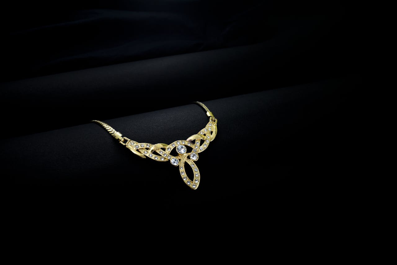 Luxury gold necklace with diamonds on elegant black background, showcasing intricate design.