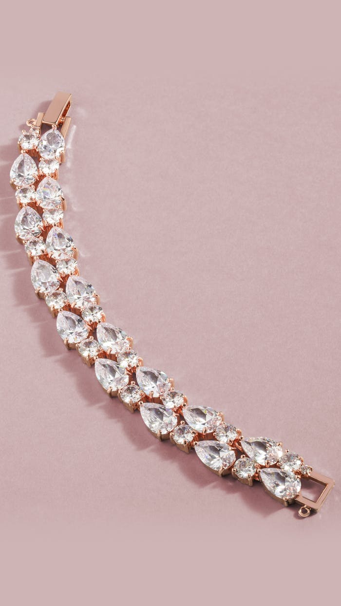 Close-up of a luxurious diamond bracelet on a soft pink backdrop, emphasizing elegance.